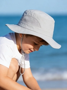 Close-up of kids grey sun hat with breathable mesh and adjustable strap on beach