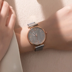 Close-up of rose gold watch with grey leaf texture dial and magnetic mesh strap on wrist