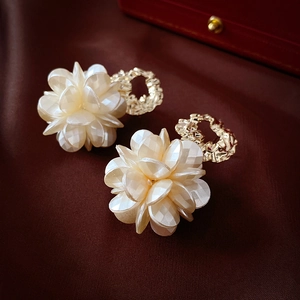 Detailed close-up of ivory acrylic flower earrings with gold hammered metal loops
