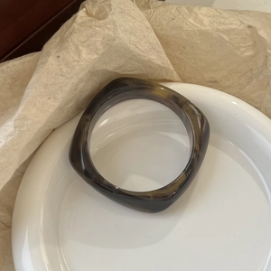 Macro view of square resin bangle with brown tortoiseshell texture and polished edges