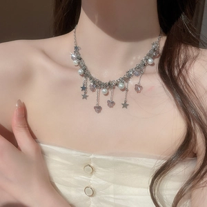 Détail d'un collier argenté avec papillon violet, pendentifs étoiles et perles