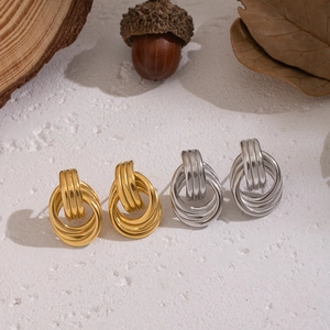 Gros plan de boucles d'oreilles nœuds géométriques entrelacés en or et argent sur bois