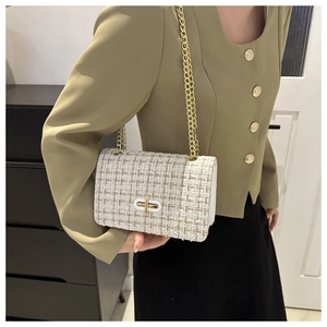 Détail d'un sac en tweed blanc avec bandoulière en chaîne dorée et fermoir sur un mannequin