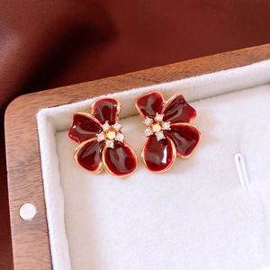 Detailed macro of wine red enamel flower earrings with sparkling zircon center