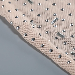 Macro detail of silver rhinestones on beige mesh fabric for a luxury two-piece outfit