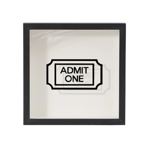 Detail of square black shadow box frame with Admit One ticket art on white background