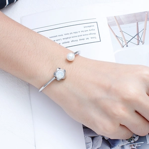 Silver flower open bangle with white pearls and crystal accents on a woman's wrist