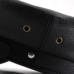 Macro detail of lychee pattern leather with vintage bronze eyelets and metallic studs