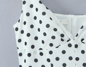 Détail du col en V et de la fermeture éclair invisible sur robe à pois blancs