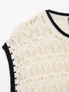 Détail macro du gilet en maille crochet crème avec liseré noir et motifs ajourés