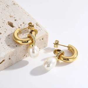 Détail de boucles d'oreilles C dorées avec perles gouttes et accents de zircon