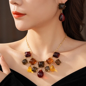 Dettaglio di orecchini e collana in resina ambrata indossati da una modella stile vintage