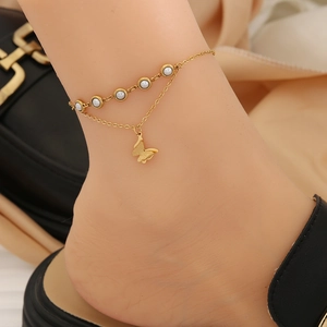 Detailed close-up of double-layer gold anklet with white pearls and butterfly charm