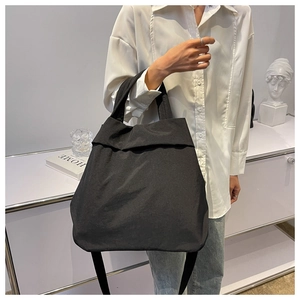 Minimalist black nylon tote bag shown in a professional lifestyle home studio setting