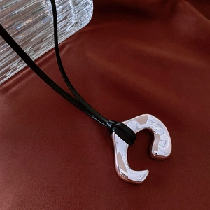 Macro shot of silver irregular curved pendant on red silk background for detail view