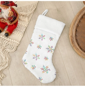 Détail d'une chaussette de Noël en peluche blanche avec des flocons en paillettes