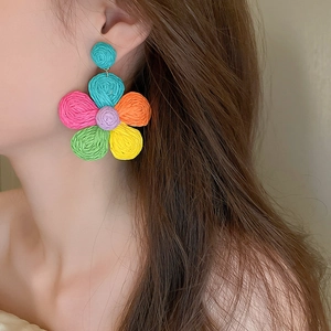 Close-up of model wearing colorful woven flower earrings for a bohemian beach style