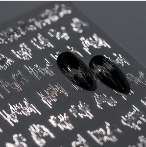 Macro shot of silver metallic nail stickers with 3D embossed letters on black fake nails