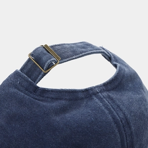 Detail of adjustable metal buckle and navy corduroy texture on retro baseball cap