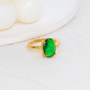 Detailed macro view of 18K gold ring featuring an oval-cut emerald in a four-prong setting