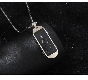 Vue macro du pendentif skateboard en acier inoxydable avec gravure LOVE et flèche de cœur