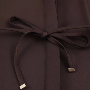 Detailed macro view of dark brown shirt fabric with ribbon belt and silver metal tips