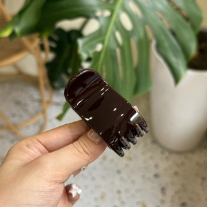 Détail d'une grande pince à cheveux marron foncé brillant en résine de haute qualité