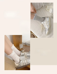 Detail of light gray socks with bow accents and silver vintage sneakers on a bed