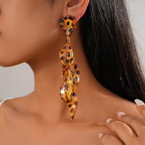 Close-up of leopard print acrylic petal fringe earrings worn by a model in soft light