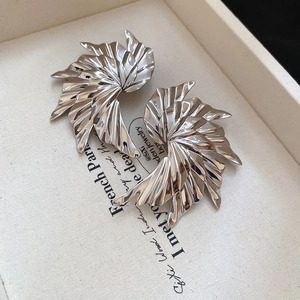 Macro detail of silver curved fan earrings with a high-gloss metallic finish