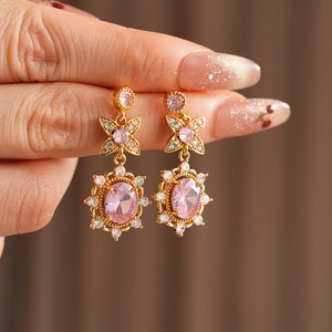 Detailed macro view of vintage gold earrings with pink oval stones and floral accents