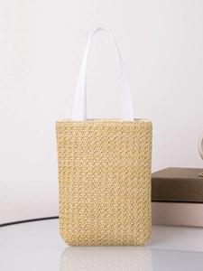 Close-up of natural straw tote bag with white woven handles in a minimalist indoor setting