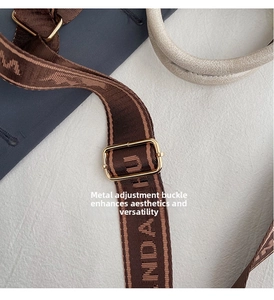 Detail of adjustable golden metal buckle on brown vintage woven strap with letter pattern