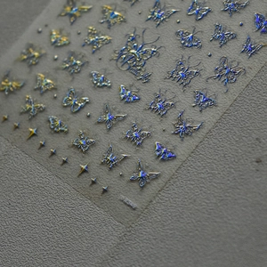 Macro shot of holographic silver butterfly nail stickers with 5D embossed metallic textures
