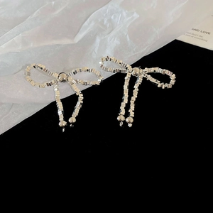 Gros plan de boucles d'oreilles nœud argentées avec cristaux brillants sur velours noir
