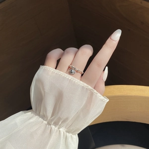 Close-up of 925 silver beaded ring with heart charm pendant on female finger