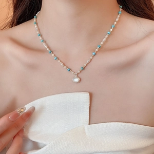 Dettaglio della collana boho con perline turchesi e ciondolo ovale in primo piano