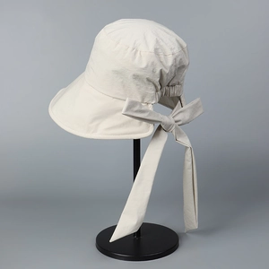 Detail of the oversized decorative bow and adjustable strap on the beige sun hat