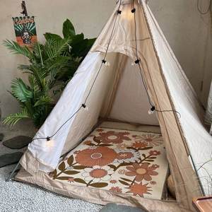 Detail of vintage floral rug inside beige canvas play tent with camping lights