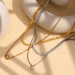 Detail of 18K gold and silver double layered snake and box chains on ceramic stand