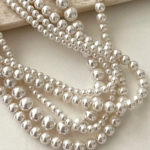 Multiple sizes of lustrous 925 silver pearl necklaces shown in a stack on textured stone