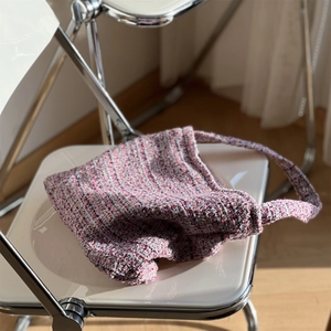 Gros plan d'un sac bandoulière en tweed rose et violet avec texture tissée sur chaise
