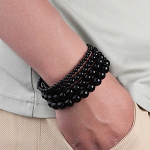 Close-up of four stacked black agate beaded bracelets in various sizes on a model wrist