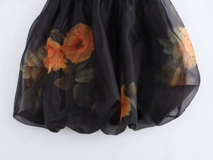 Gros plan détaillé de l'ourlet de robe en organza noir avec motif floral orange et tulle