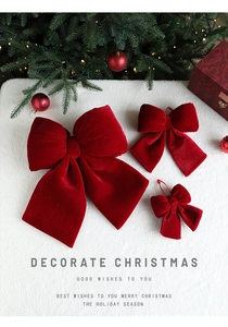 Three sizes of red velvet Christmas bows displayed on white fur with festive decor