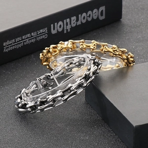 Detail of punk style skull bone link bracelets in gold and silver stainless steel finish