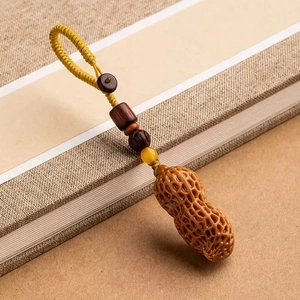 Macro detail of sandalwood peanut pendant with woven rope on vintage book background