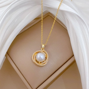 Close-up of bird nest gold necklace with pearl and sparkling zircon on silk background