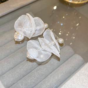 Detailed macro view of white fabric flower earrings featuring elegant hanging pearls