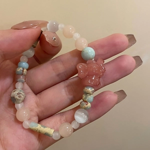 Macro detail of multicolored natural gemstone bead bracelet with pink elephant charm
